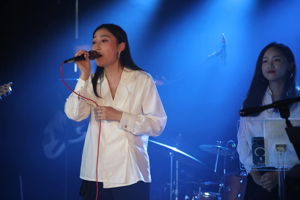 Two vocalists performing under a cool blue light wash
