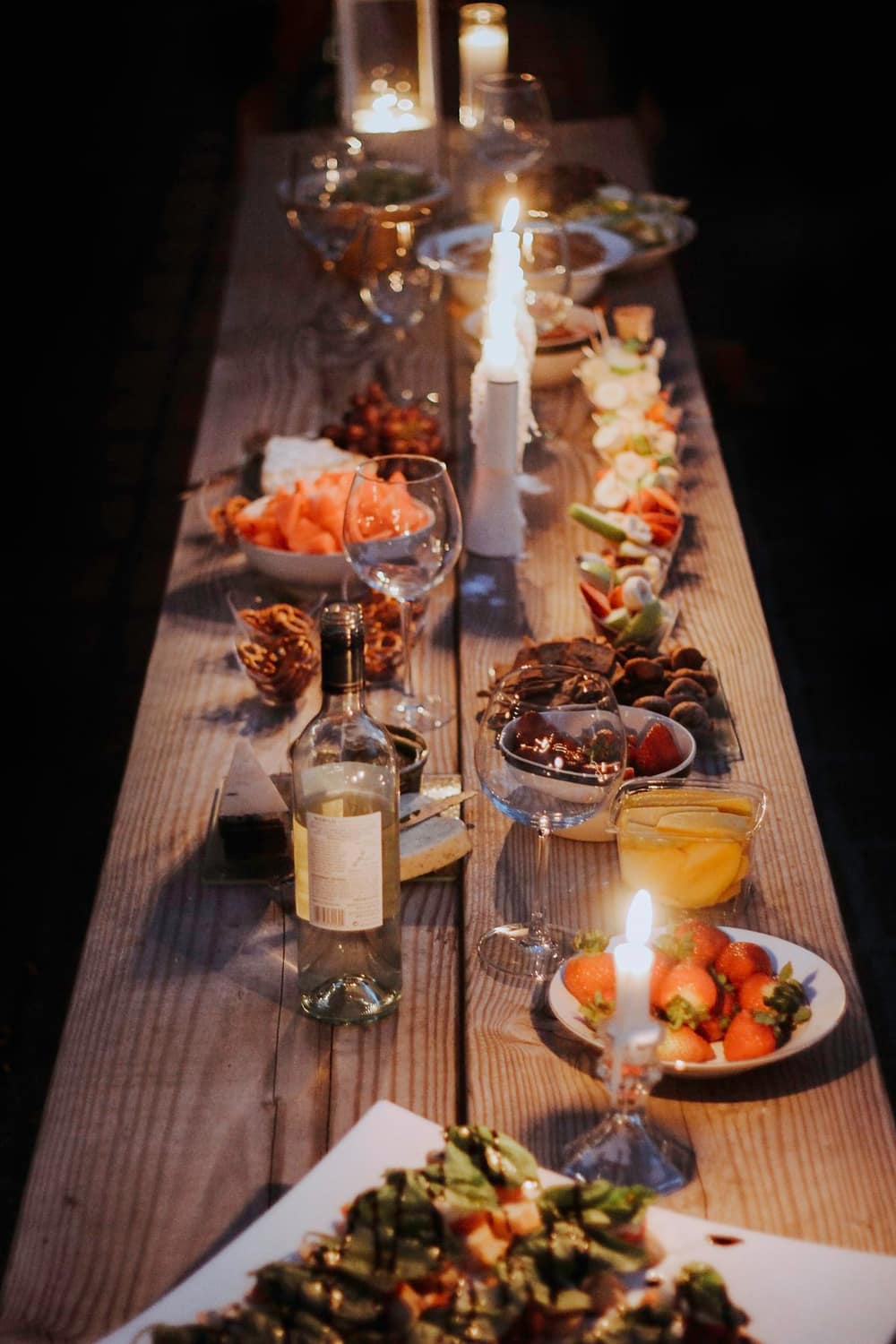A long dinner table lit by candlelight