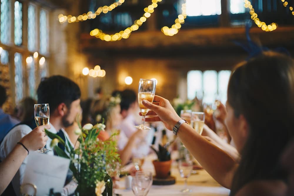 Guests raising champagne glasses under warm string lights